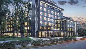 A modern hotel with a prominent "DOUBLETREE by Hilton" sign, large windows, and a well-maintained outdoor area with trees and a pathway. - Doubletree By Hilton Plovdiv Center (Plovdiv)