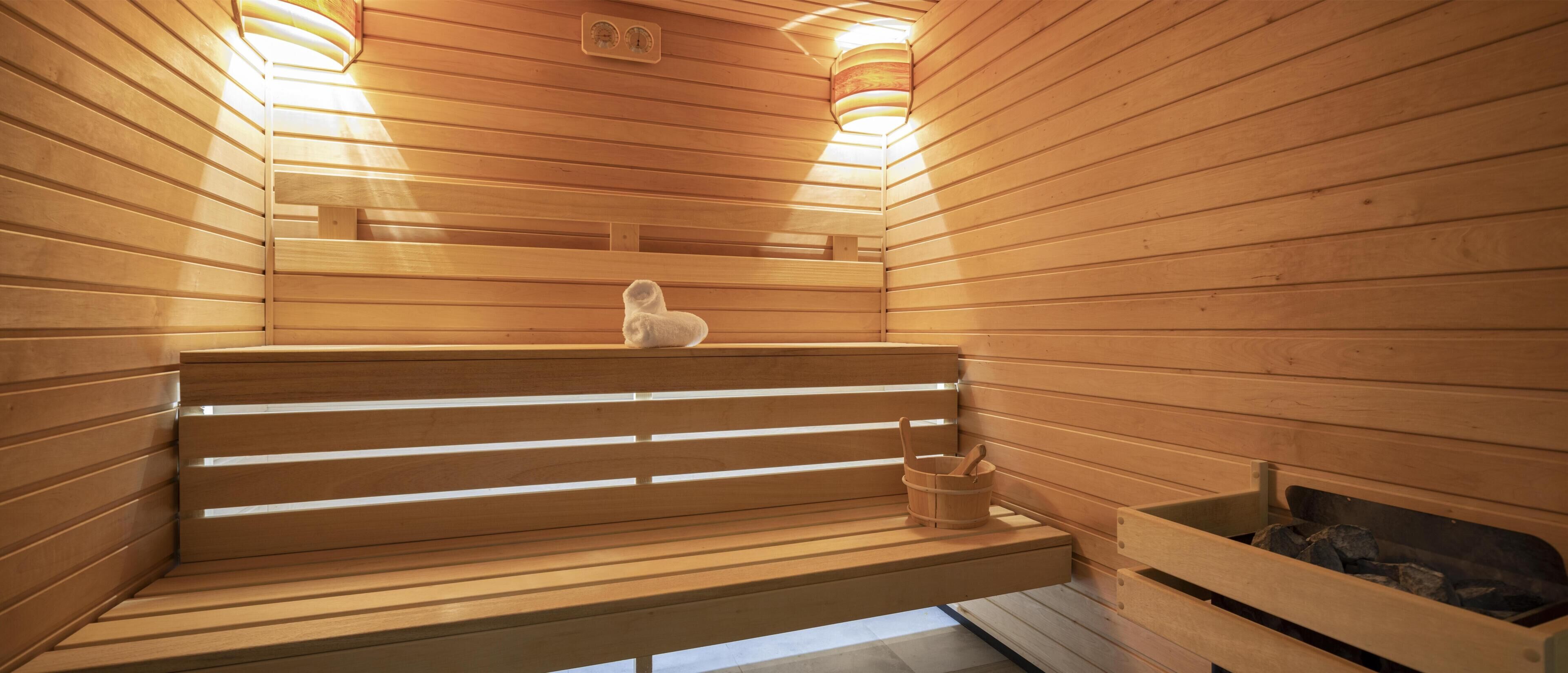 Un sauna en bois avec des bancs et un petit seau en bois.