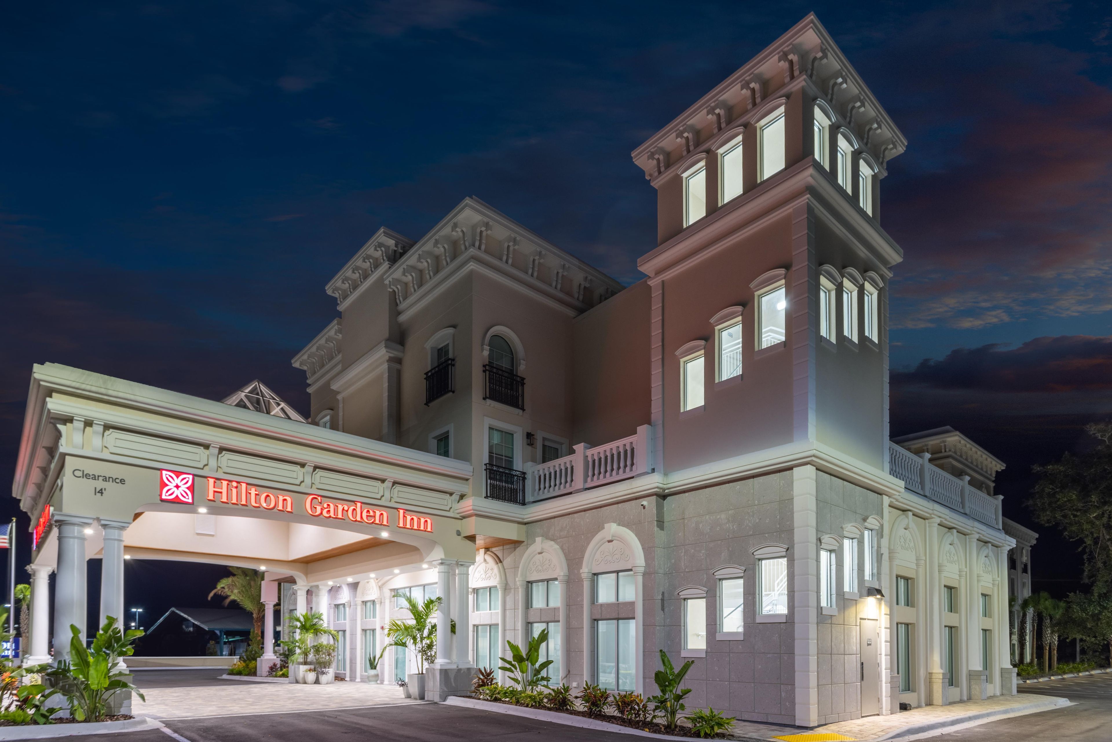 A large, multi-story hotel with a classic architectural style, featuring a prominent entrance and a sign for the Hilton Garden Inn.