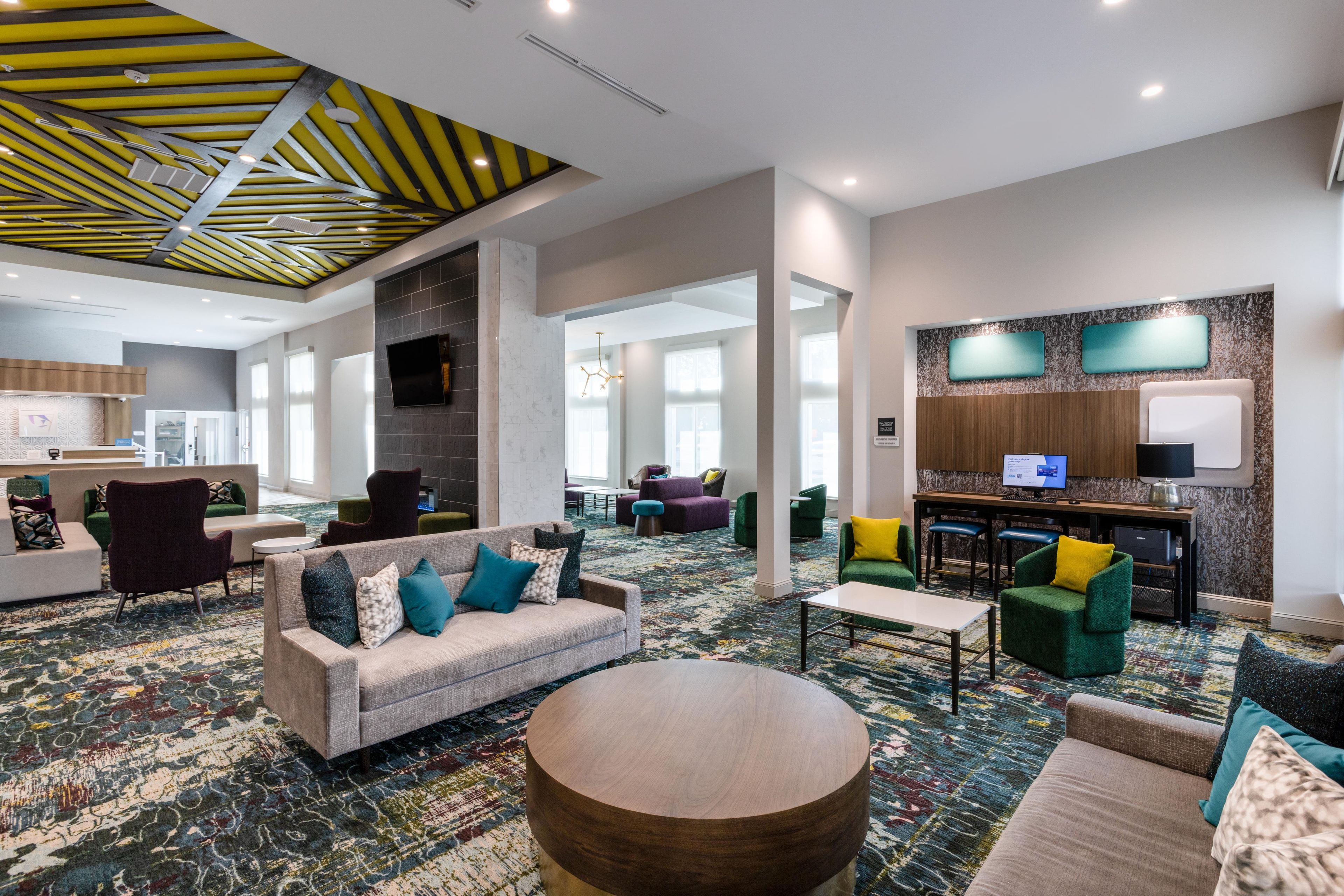 Un vestíbulo de hotel con diseño moderno, que incluye zonas de estar variadas, un bar y una chimenea.