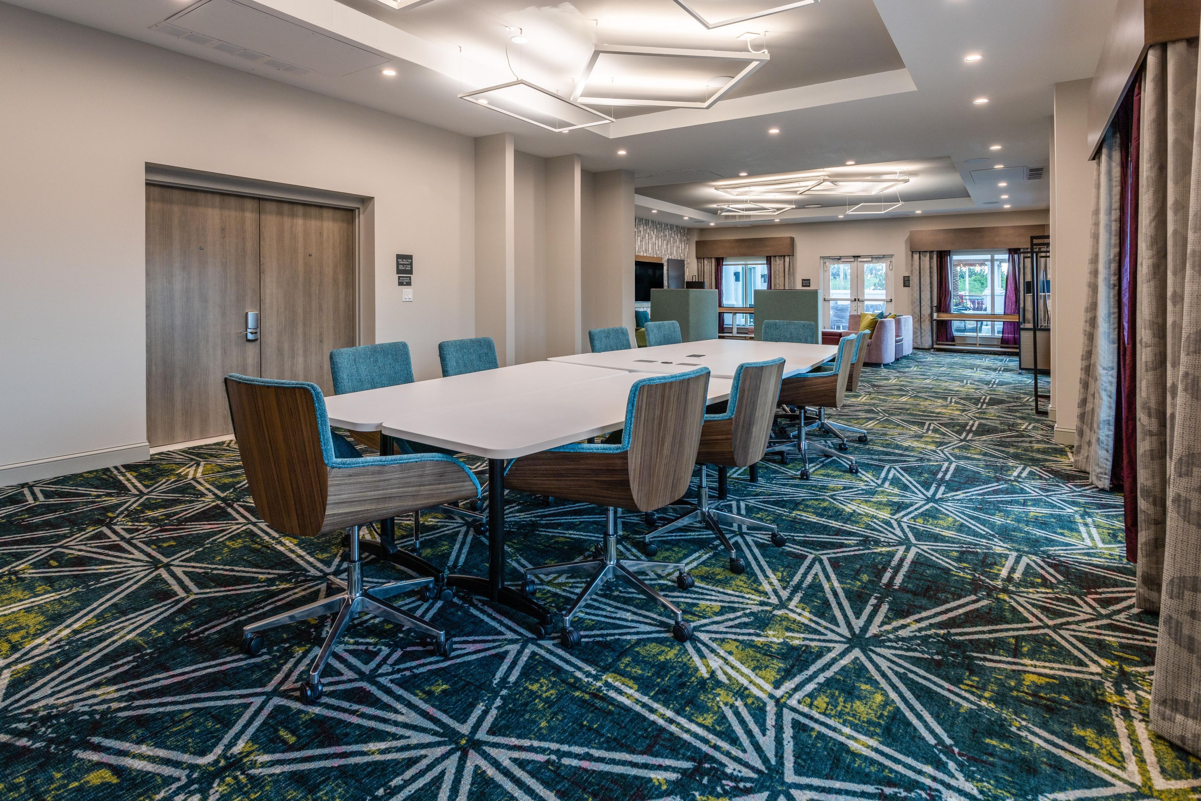 A conference room with a long table, chairs, and a patterned carpet.
