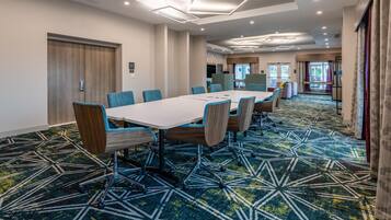 A conference room with a long table, chairs, and a patterned carpet.
