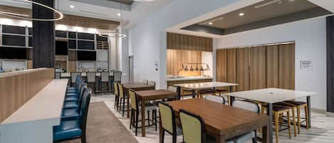 Un comedor moderno con una barra larga, varias mesas y sillas.