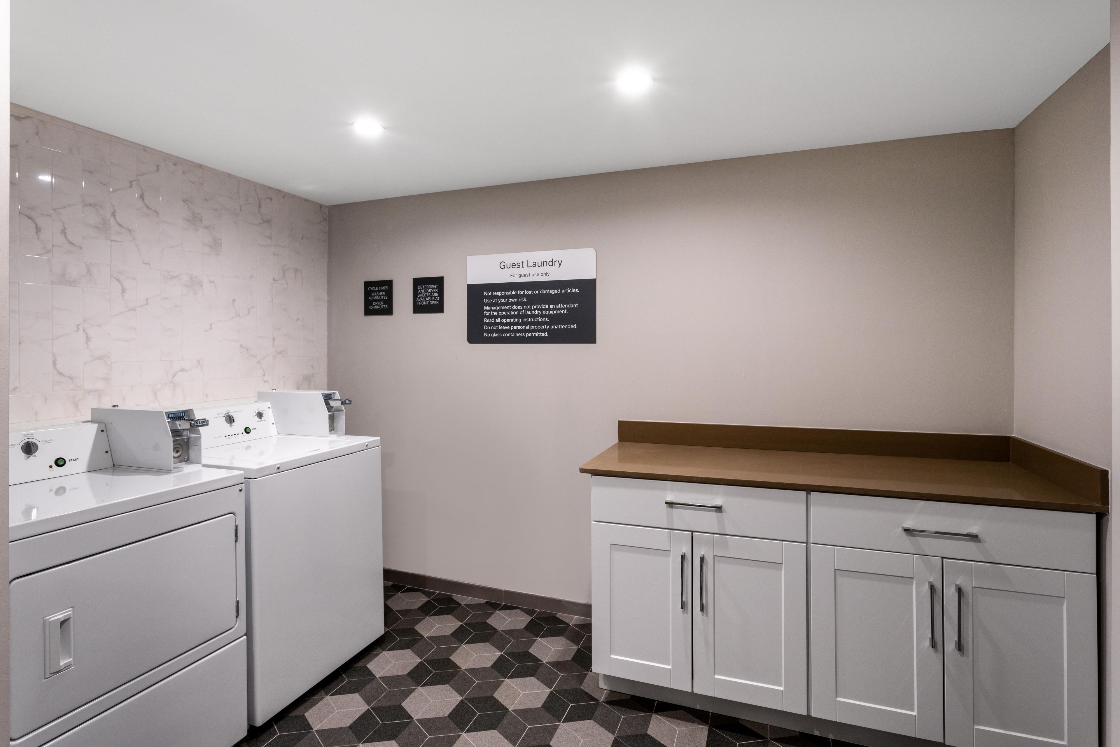 A guest laundry area with a washing machine, dryer, and a sign indicating guest use only.