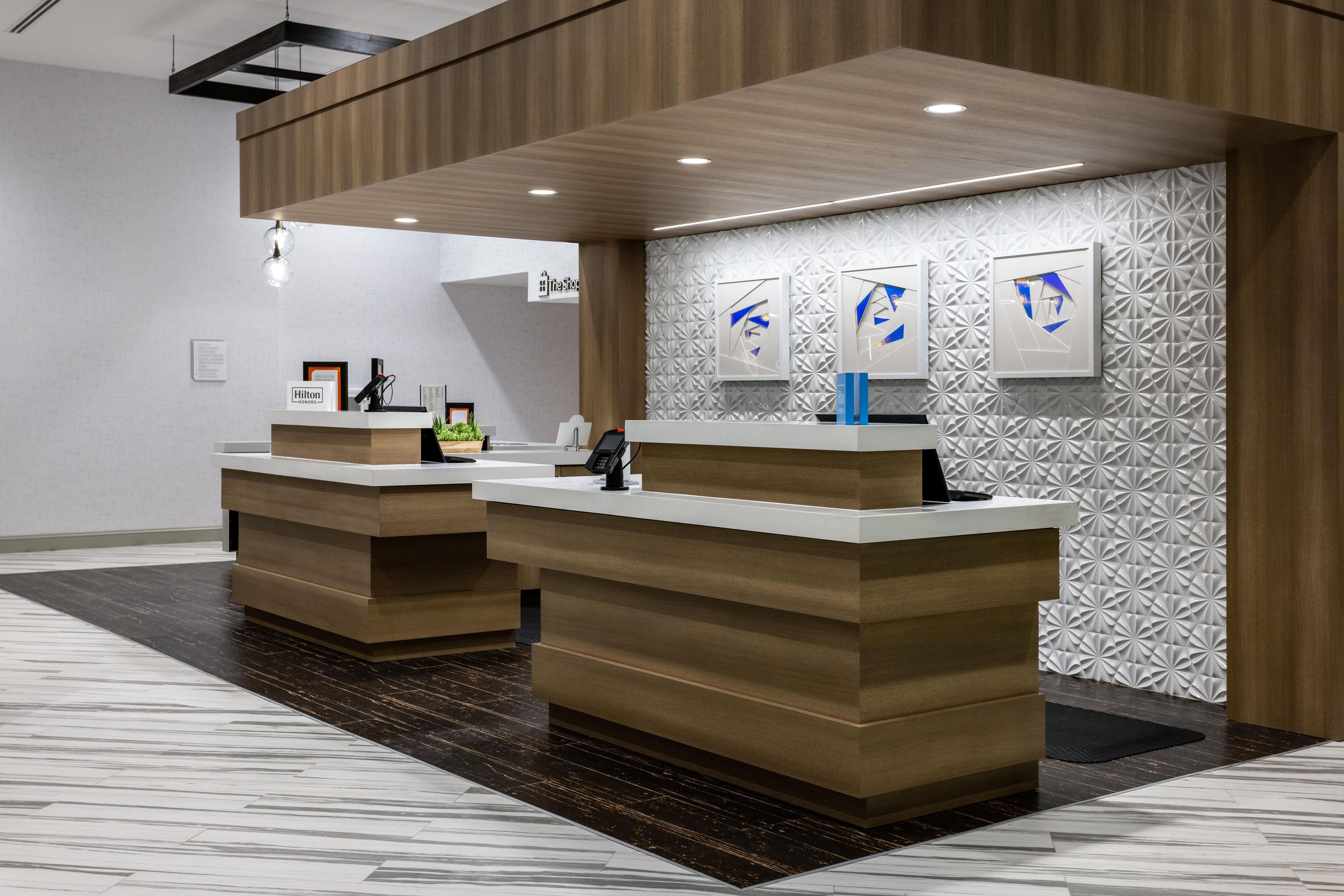 Ein Hotel-Empfangsbereich mit zwei Empfangstresen, modernem Design und einer Wand mit Muster.