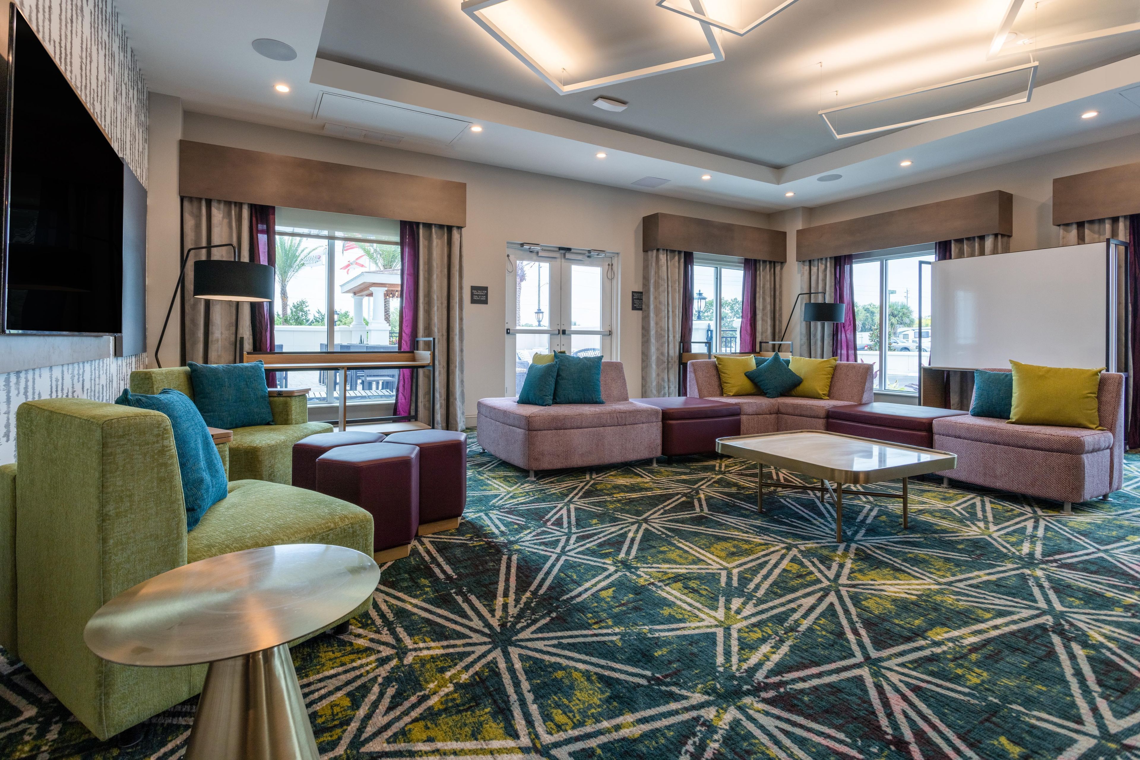 A modern hotel lobby with a sectional sofa, a round coffee table, and a patterned carpet.