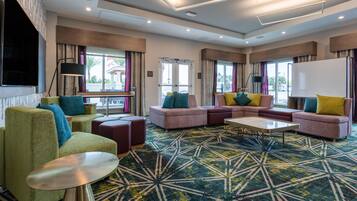 A modern hotel lobby with a sectional sofa, a round coffee table, and a patterned carpet.