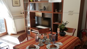 Un coin repas avec une table dressée pour deux personnes, agrémentée de croissants et d’une cafetière.