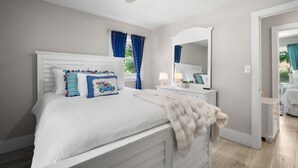 Een slaapkamer met een groot bed, een kaptafel, een spiegel en een plafondventilator.