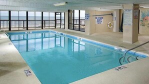 Une piscine intérieure offrant une vue dégagée sur l’océan grâce à de grandes baies vitrées.