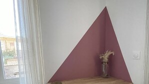 A corner desk with a triangular backrest, a chair, a vase with dried flowers, and a window with curtains. - L'Appartement Bleu - Cosy apartment - Heart of town (Douai)