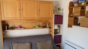 A compact living space with a grey sofa, wooden cabinets, and a white radiator.