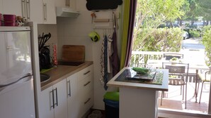 A compact kitchen with white cabinets, a built-in oven, and a small dining area with a table and chairs.