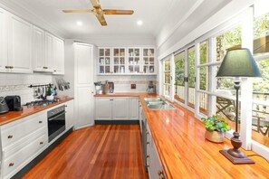 A kitchen with wooden flooring, white cabinets, a built-in oven, and a window with a view of greenery.