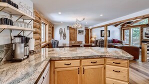 Una cocina amplia con encimeras de granito, armarios de madera y un comedor con mesa y sillas.