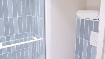 Een badkamer met een douche met glazen wand, een toilet en een vloer met marmerpatroon.