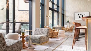 A modern hotel lobby with large windows, comfortable seating, and a bar area. - Hotel Yac Paris Clichy, A Member Of Radisson Individuals (Clichy)