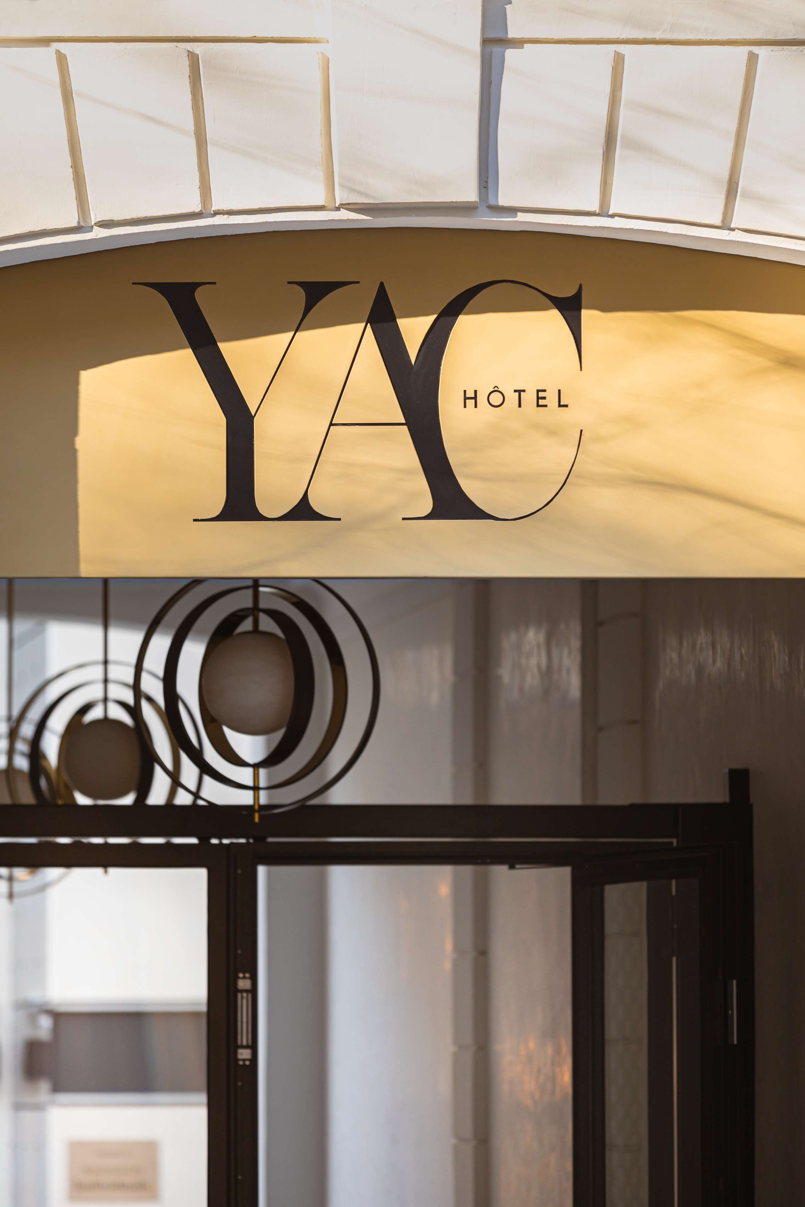 A hotel sign with the name "YAC HOTEL" and a modern interior with circular light fixtures.