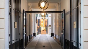 A hallway with a modern chandelier, black metal gates, and a view into a warmly lit interior space. - Hotel Yac Paris Clichy, A Member Of Radisson Individuals (Clichy)