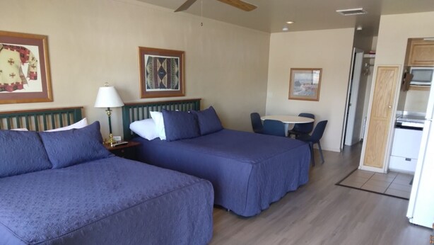 A hotel room with two beds, a desk, and a chair.