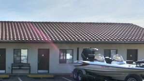A building with a tiled roof, numbered doors, and a parking lot with a red truck and a boat trailer.
