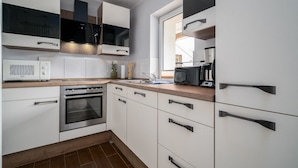 A modern kitchen with white cabinets, stainless steel appliances, and a wooden countertop. - Vacation apartment Mila am Schwarzer See - Lake District (Schwarz)