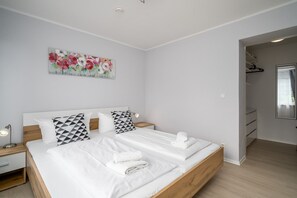 A modern hotel room with a large bed, a nightstand, a wall-mounted painting, and a walk-in closet.
