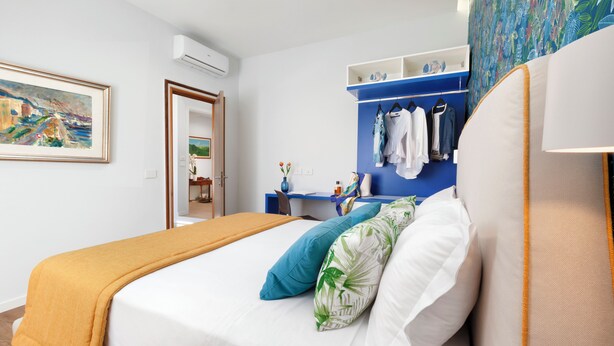 A hotel room with a bed, a desk, and a wardrobe.
