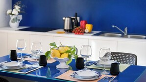 A dining table set with white plates, black napkins, and clear wine glasses, with a bowl of lemons and a pitcher on the table.