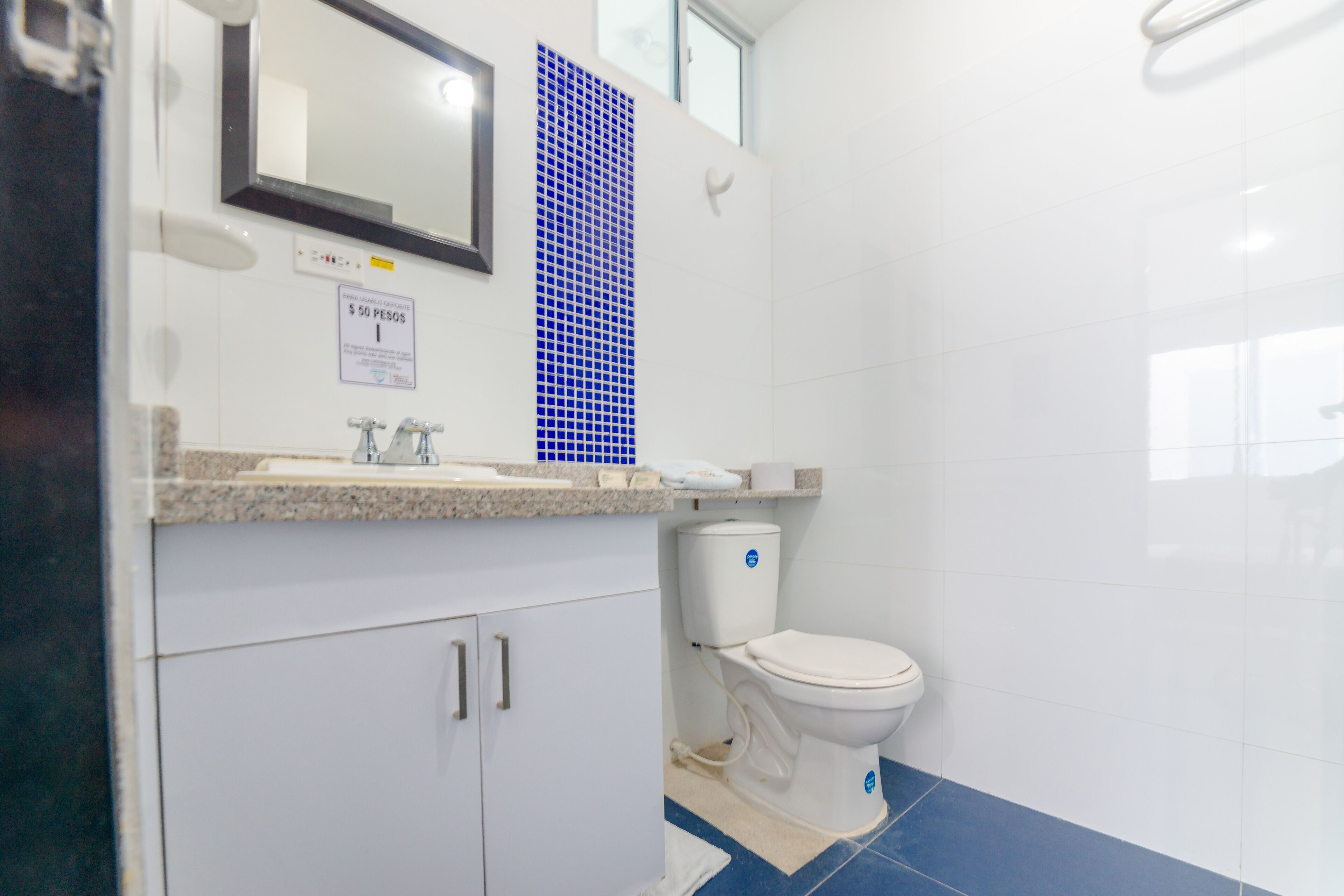 A bathroom with a white sink, mirror, and toilet.