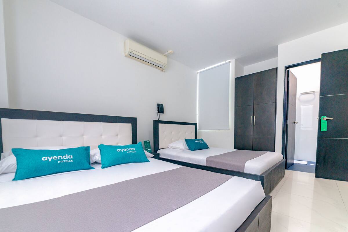 Quarto de hotel com duas camas, cada uma com cabeceira, TV de tela plana e minibar.
