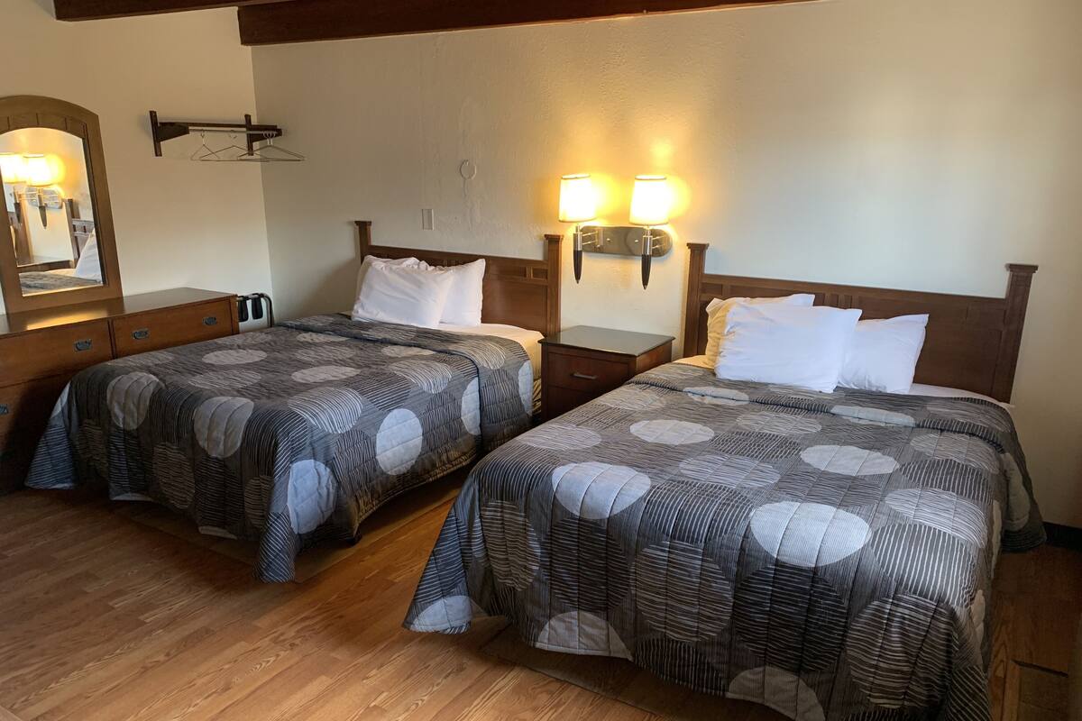 Two double beds with matching headboards, bedside tables, and wall-mounted lamps.