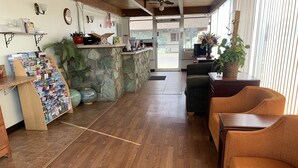 A reception area with a stone wall, wooden floor, and wicker furniture. - Fort Collins Inn (Fort Collins)