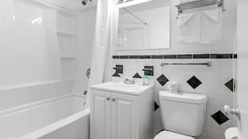 Un baño con bañera, inodoro, lavabo y espejo.