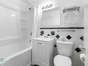 A bathroom with a bathtub, toilet, sink, and a mirror.