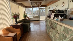 A reception area with a stone counter, wooden furniture, and a view of the street outside. - Fort Collins Inn (Fort Collins)