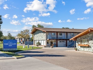 A hotel with a stone facade, a covered entrance, and a signboard. - Fort Collins Inn (Fort Collins)