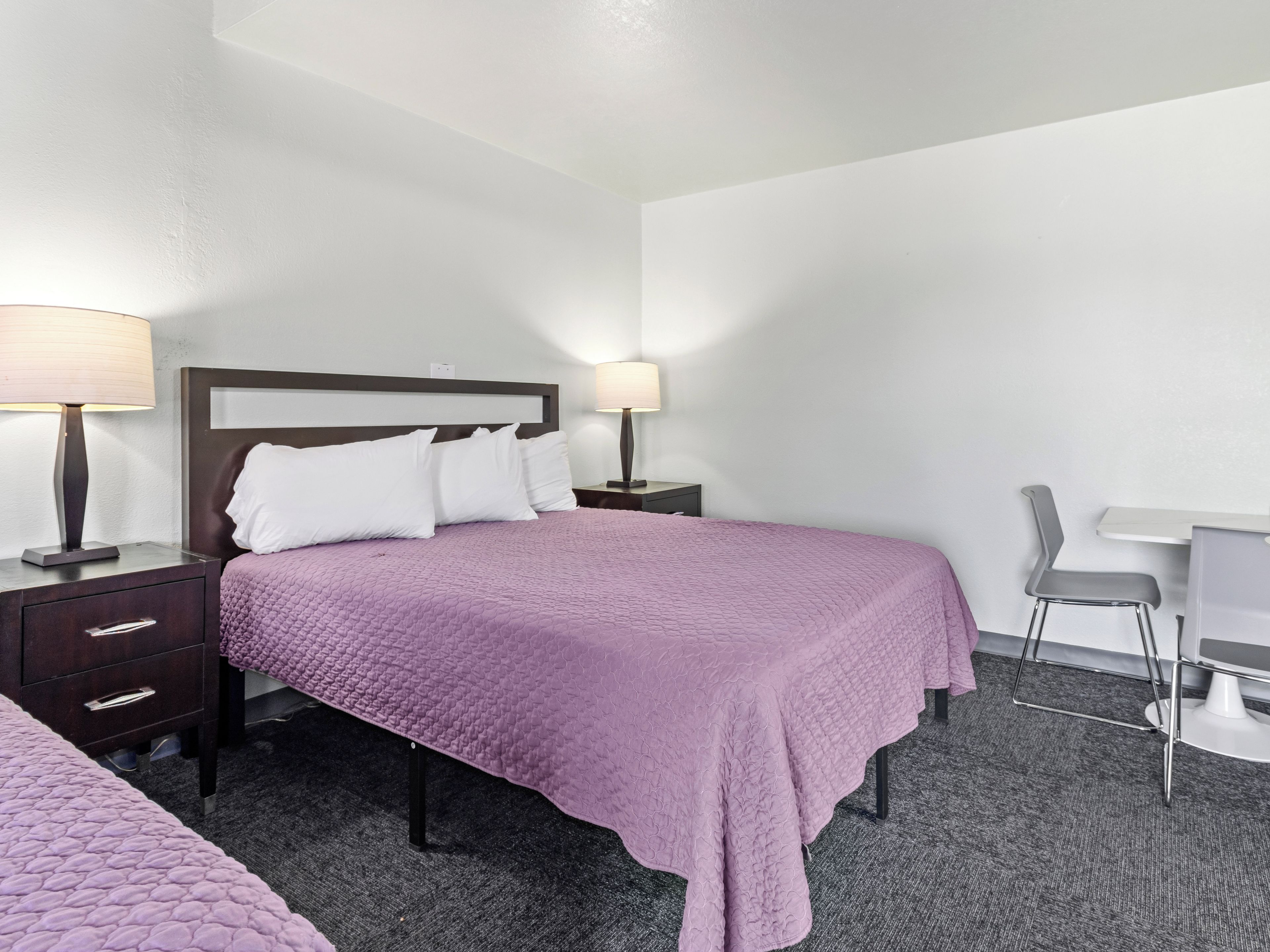 Habitación de hotel con una cama, dos mesitas de noche, un escritorio y una silla.