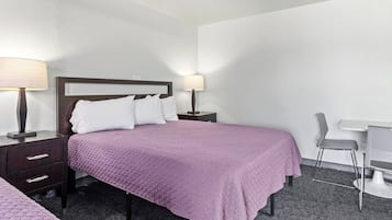 Habitación de hotel con una cama, dos mesitas de noche, un escritorio y una silla.