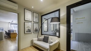Un espacio de oficina moderno con suelo de madera, un sofá blanco y cuadros de la ciudad enmarcados en la pared.