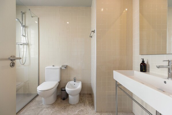 Une salle de bain moderne équipée de toilettes, d’un bidet et d’une douche.