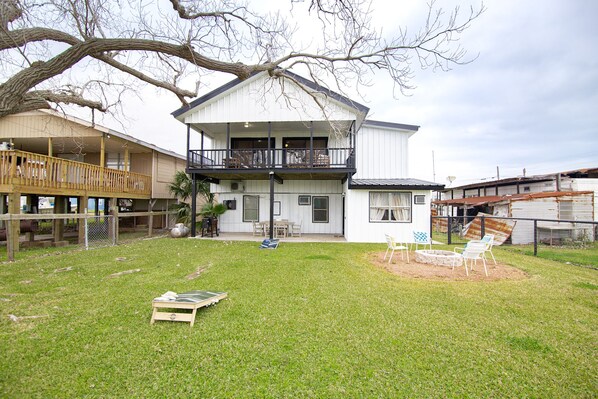 A two-story house with a balcony, a fenced yard, and outdoor furniture.