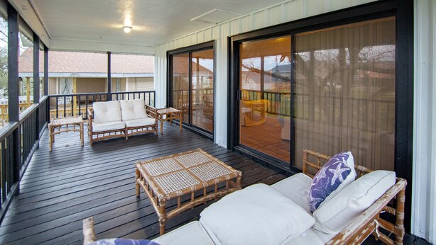 A covered outdoor area with wicker furniture, including sofas and a table, and large sliding glass doors. - Spacious Vacation Home: Sleeps 16, 1/2 mi to Beach & Boat Ramp - Family Friendly (Port O'Connor)