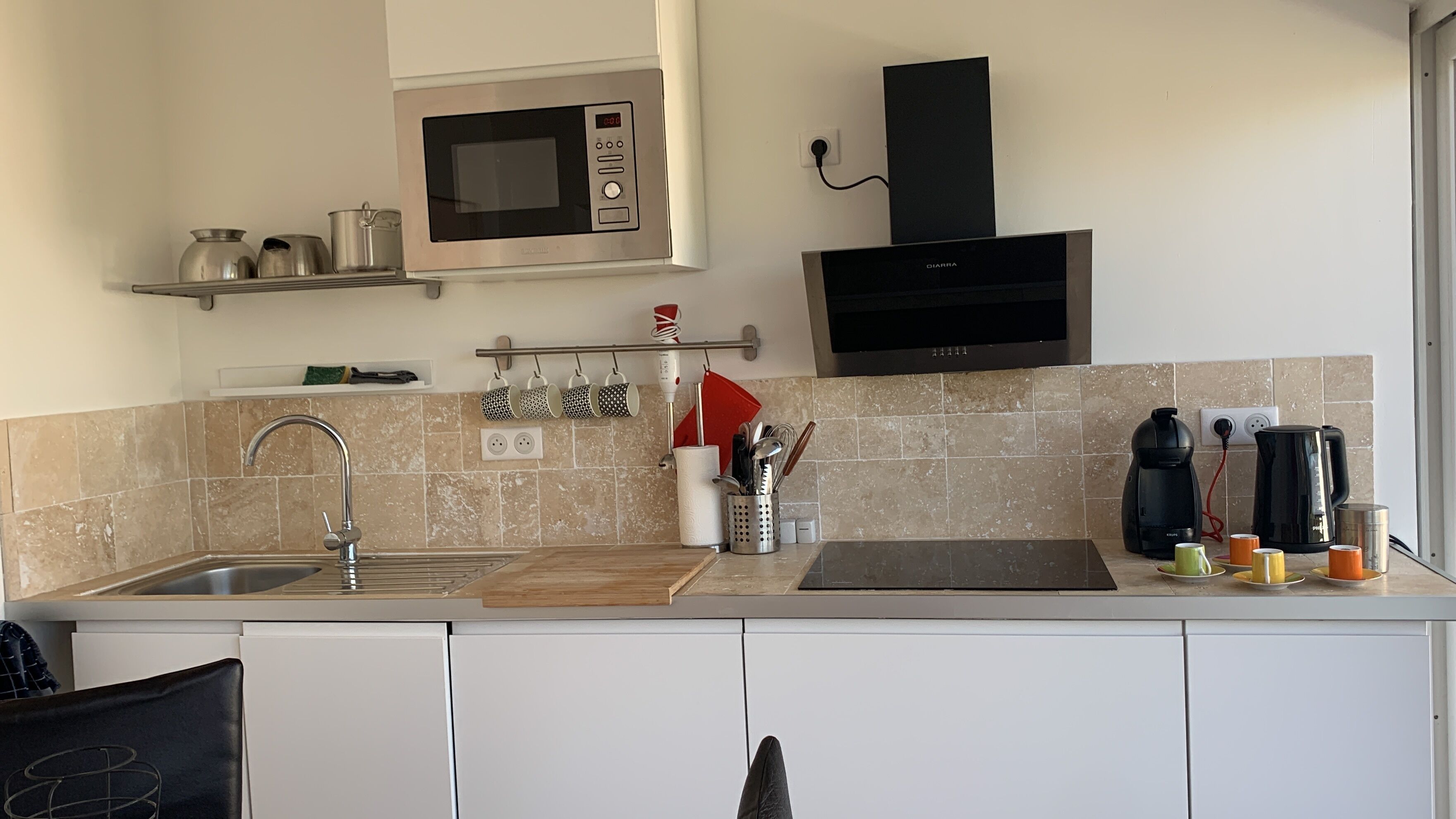 A modern kitchen with a built-in microwave, a coffee maker, and a kettle.