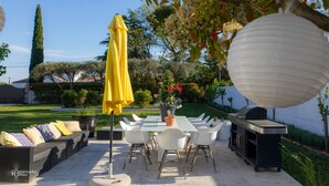 An outdoor patio with a dining table, chairs, a yellow umbrella, and a grill. - Croissant de Lune (Bagard)