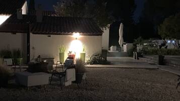 A house with a tiled roof, a patio with a chair and table, and a car parked outside.