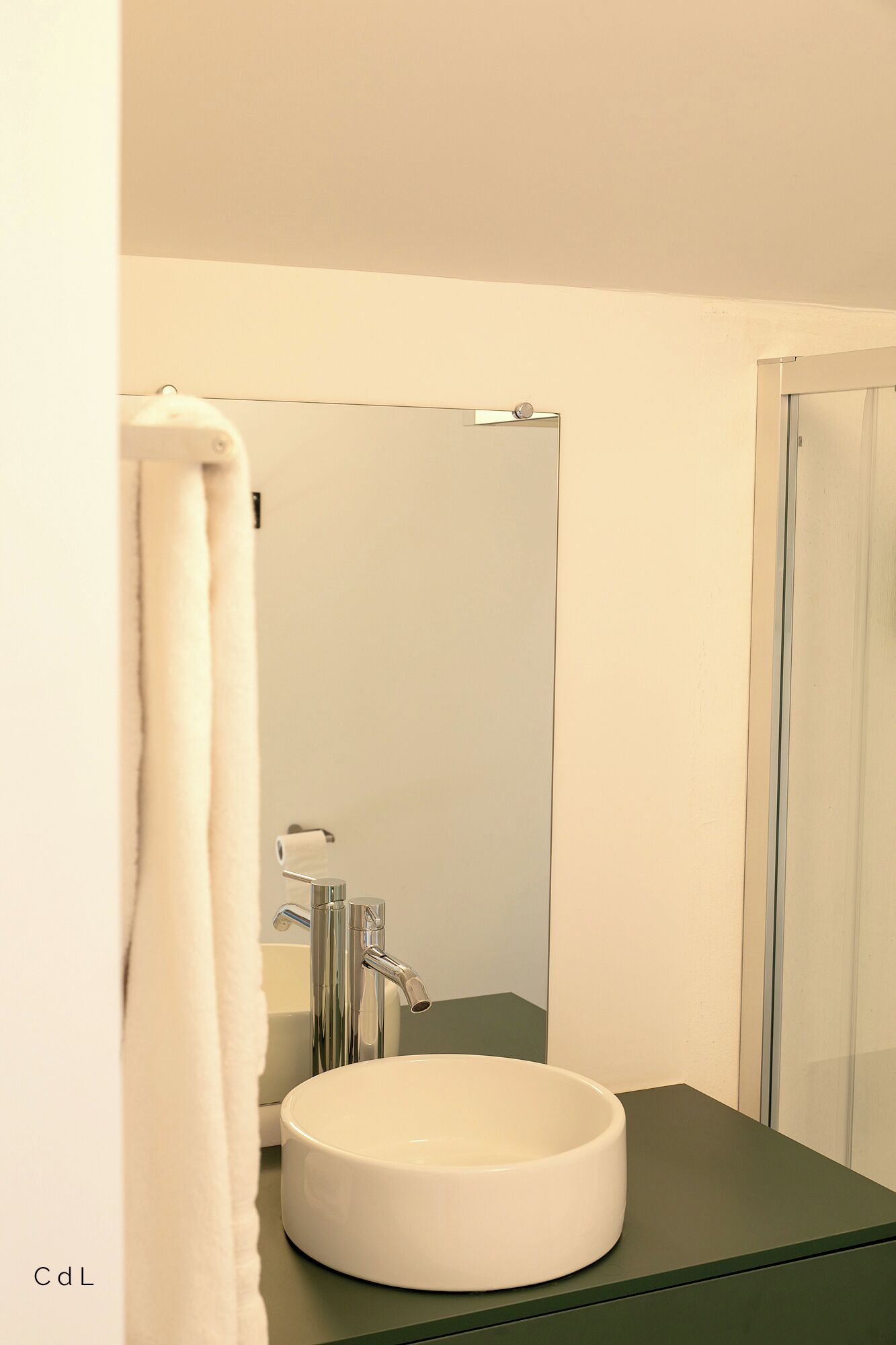 Une salle de bain avec un lavabo rond blanc, un miroir et une douche.