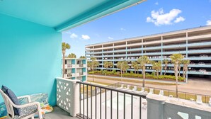 A balcony with a view of a multi-level parking garage, outdoor seating, and a pool area. - Lovely Studio Condo 200 Yards from the Atlantic (Myrtle Beach)