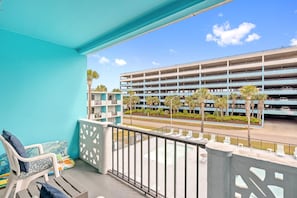 A balcony with a view of a multi-level parking garage, outdoor seating, and a pool area. - Lovely Studio Condo 200 Yards from the Atlantic (Myrtle Beach)