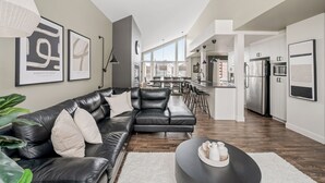A modern living room with a leather sofa, a coffee table, and artwork on the walls. - 24-Chalet à Stoneham (Stoneham-et-Tewkesbury)